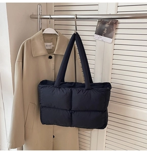 Close-up of black quilted puffer tote bag hanging on a metal rack in a lifestyle setting