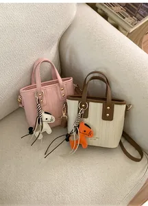 Detailed view of mini woven tote bags with horse charms on a soft fabric sofa