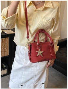 Detail of red baguette bag with star charm and premium litchi grain texture finish