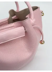Detail der rosa Leder-Eimertasche mit feinen Nähten und metallischen Kugelanhängern