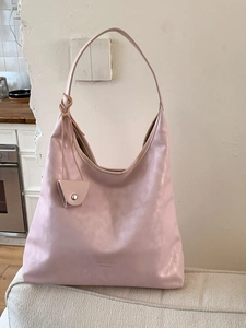 Pink oversized hobo tote bag with matching coin pouch on a white sofa scene