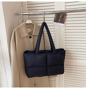 Close-up of black quilted puffer tote bag with soft nylon texture and wide handles