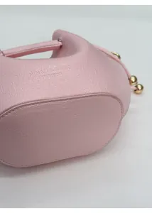 Detail der rosa Beuteltasche mit verstärktem Boden und Logoprägung auf Litschi-Textur