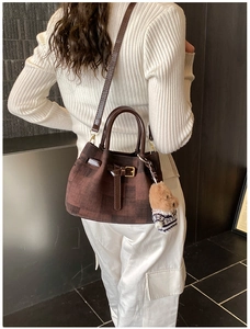 Detail einer braun karierten Beuteltasche mit süßem Teddybär-Anhänger an einem Model