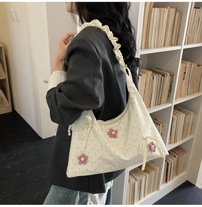 Close-up of white polka dot bag with red floral accents and ruffled shoulder strap