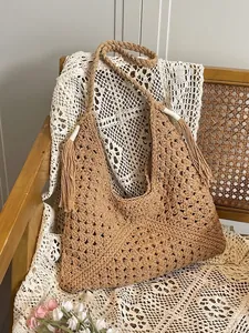 Brown hand-woven crochet tote bag with fringe details on a vintage chair