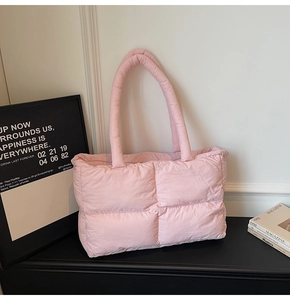 Close-up of pink quilted puffer tote bag on a modern display with minimalist decor