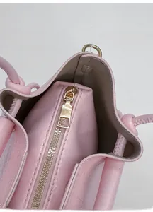Nahaufnahme der rosa Beuteltasche mit zentralem Reißverschlussfach und grauem Innenfutter