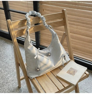Close-up of floral tote bag with pleated handle and ribbon bow on a wooden chair