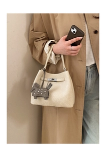 Detail of off-white lychee grain leather bucket bag with silver lock and pony charm