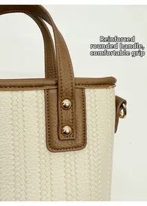 Detail of woven bucket bag with brown leather reinforcement and golden metal rivets