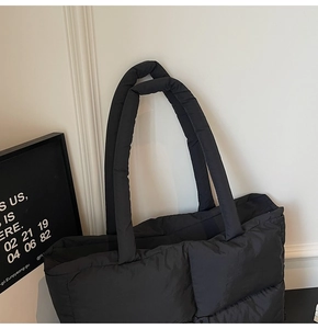 Macro detail of high-capacity black quilted tote bag with soft padded nylon texture
