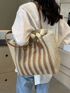 Fashionable large woven straw tote bag with brown leather straps and striped texture