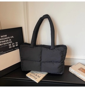 Close-up of black quilted puffer tote bag with thick shoulder strap and padded texture