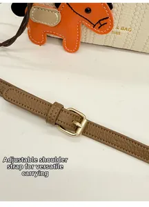 Detail of adjustable leather strap with golden buckle and horse charm on a woven bucket bag