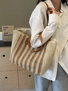 Large striped straw tote bag with brown leather straps shown on a female model