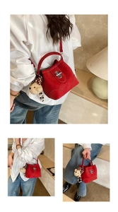 Detail of red bucket bag featuring suede texture, silver metal twist lock, and a cute bear charm