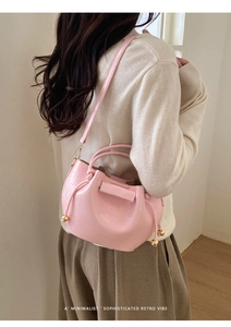 Seitenansicht der rosa Falten-Beuteltasche mit Goldkugeln und Kordelzugverschluss