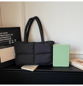 Quilted black puffer tote bag on display next to a green tablet for size reference