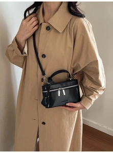 Mannequin portant un sac bandoulière carré en cuir noir avec double fermeture éclair