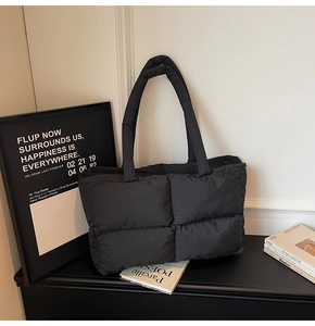 Detail of the black quilted puffer tote bag showing the soft padded nylon fabric texture