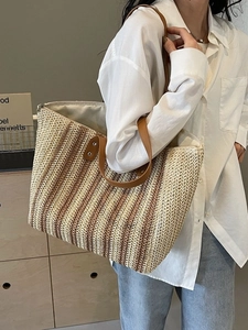 Large woven straw tote bag with color-block stripes and brown leather straps for beach vacation
