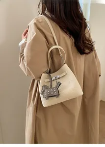 Detail of elegant beige bucket bag with lychee grain leather and silver twist lock
