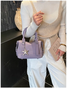 Detail of lavender bowling bag featuring a silver starfish charm and textured leather finish