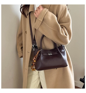 Detailed side view of a vintage soft leather bucket bag with beaded tassel and metal clasp
