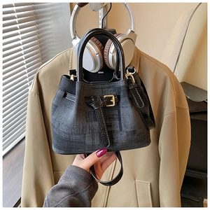 Detailansicht der Denim-Beuteltasche mit schwarzem Lederbesatz und goldenen Metallteilen