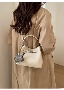Detail of cream pebbled leather bucket bag with metal lock and horse charm decoration