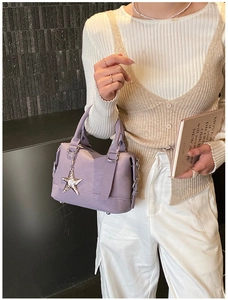 Close-up of lavender leather handbag with silver star pendant and ring zipper pull