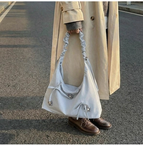 Close-up of ruched shoulder strap with 3D bow and daisy charm on light grey tote bag