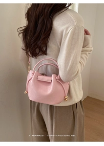 Detail der rosa Kordelzug-Beuteltasche aus Leder mit Narbung und goldenen Akzenten