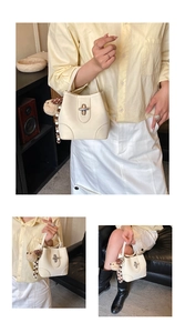 Detail of cream leather handbag featuring a twist lock and cute teddy bear plush charm