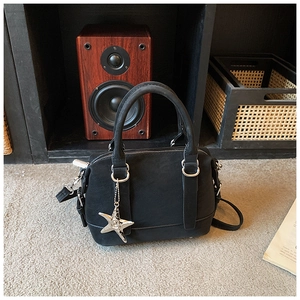 Black suede bowling bag on a plush carpet featuring a silver starfish charm detail