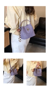 Detail view of purple bucket bag with plush bear charm and decorative pearl chain