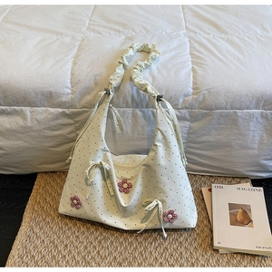 Close-up of beige polka dot canvas bag with red plaid floral patches and bow detail