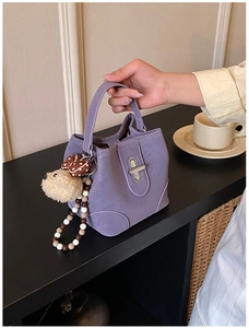 Detail of purple bucket bag with silver turn-lock and cute plush dog pendant charm