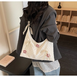 Detailed back view of a white polka dot tote bag with floral charms and a ribbon bow