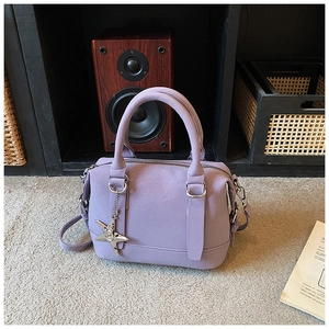 Close-up of lilac pebbled faux leather boston bag with a silver star charm detail