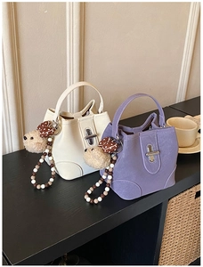 Detail of mini leather bucket bags in cream and lilac with decorative bear charms