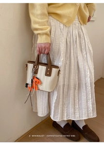 Detail of a vintage cream bucket bag with textured pattern and decorative horse charm