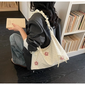 Detailed view of white floral tote bag with red gingham flowers and ruffle strap