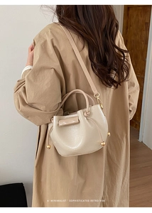 Detail einer beigen Eimertasche aus Leder mit goldenen Elementen und Kordelzug