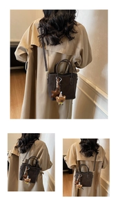 Detailansicht braune Wildledertasche mit weißen Nähten und Bärenanhänger zum Trenchcoat