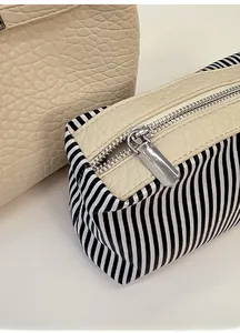 Detail of smooth silver metal zipper on a black and white striped bucket bag