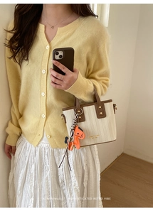 Detail of minimalist bucket bag featuring contrast stitching and a decorative horse charm