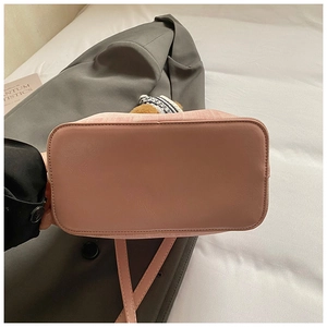 Detailansicht der rosafarbenen Mini-Beuteltasche mit Ziernähten und Bärenanhänger