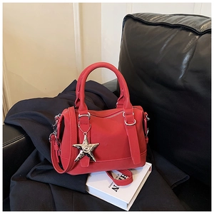 Detail of red bowling bag with silver starfish charm on a black leather background